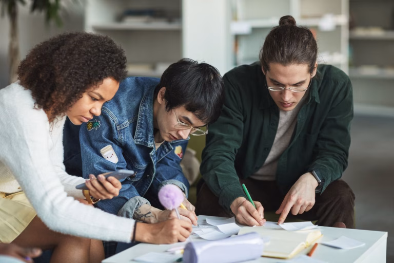 Multiracial group of young adults collaborating on a study project in a modern library.